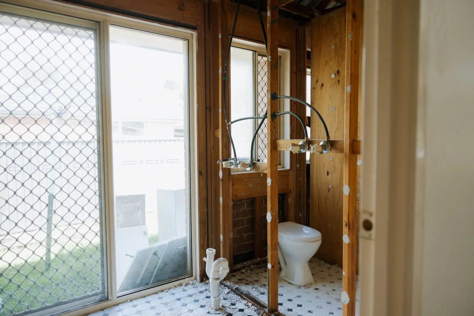 Bathroom gut renovation Taigum Brisbane — stripped walls and plumbing exposed before full bathroom refit