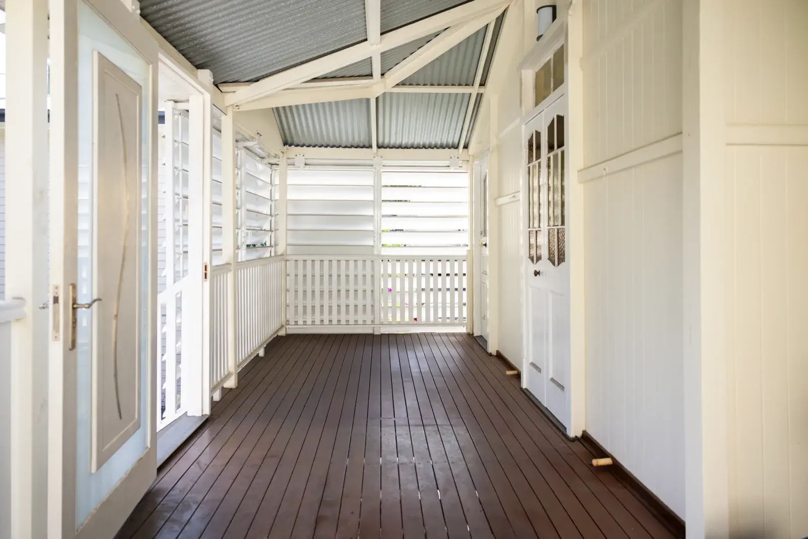 Before photo — open Queenslander verandah with louvres and dark timber flooring prior to renovation by Farr Constructions