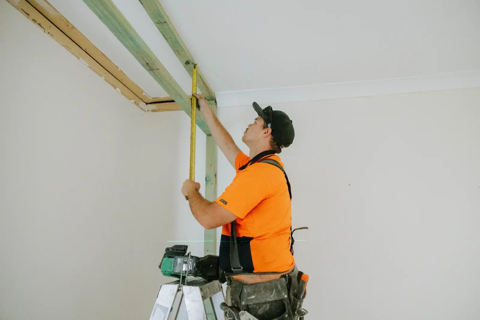 Tradesman measuring new ceiling framing during bedroom renovation in Taigum Brisbane