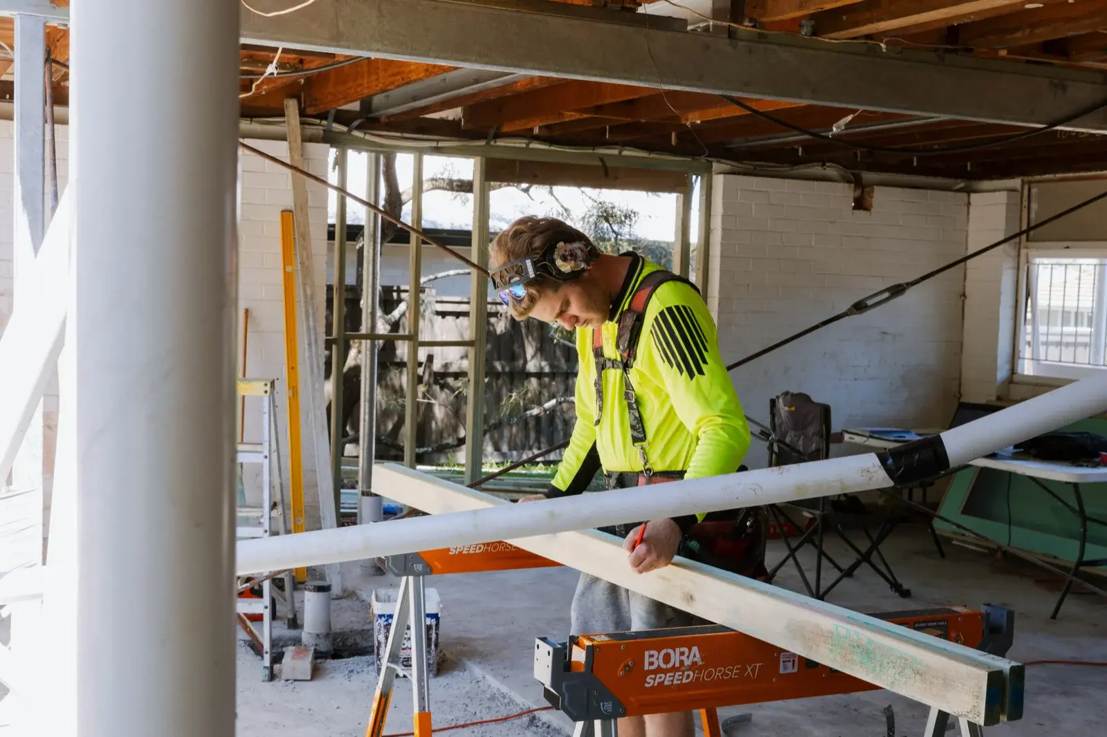 Farr Constructions carpenter measuring timber precisely on a sawhorse at a Brisbane renovation site — illustrating the quality control a professional builder provides