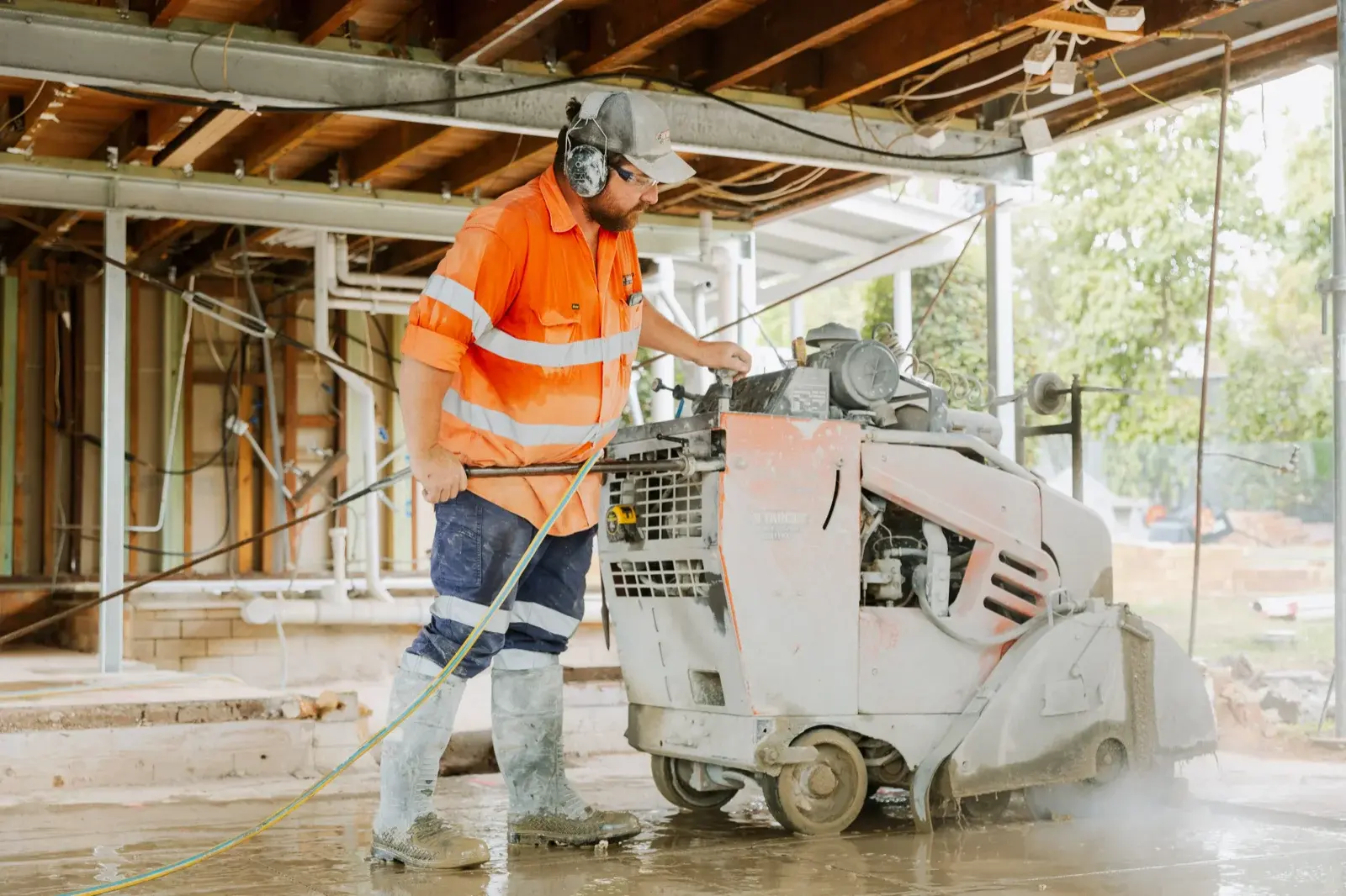Farr Constructions tradesman operating a concrete floor saw during a large-scale home renovation in Brisbane — efficient on-site coordination in action