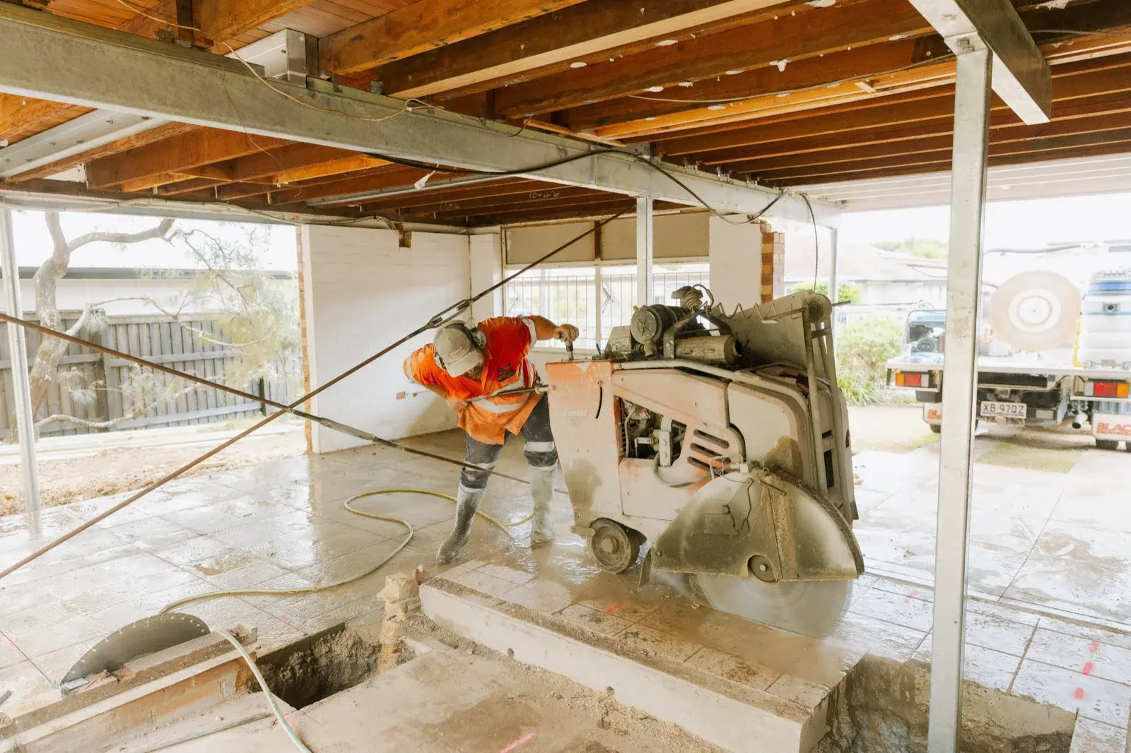 Farr Constructions tradesman cutting and removing old concrete slab using a floor saw, showing the scale of demolition during a Brisbane home renovation