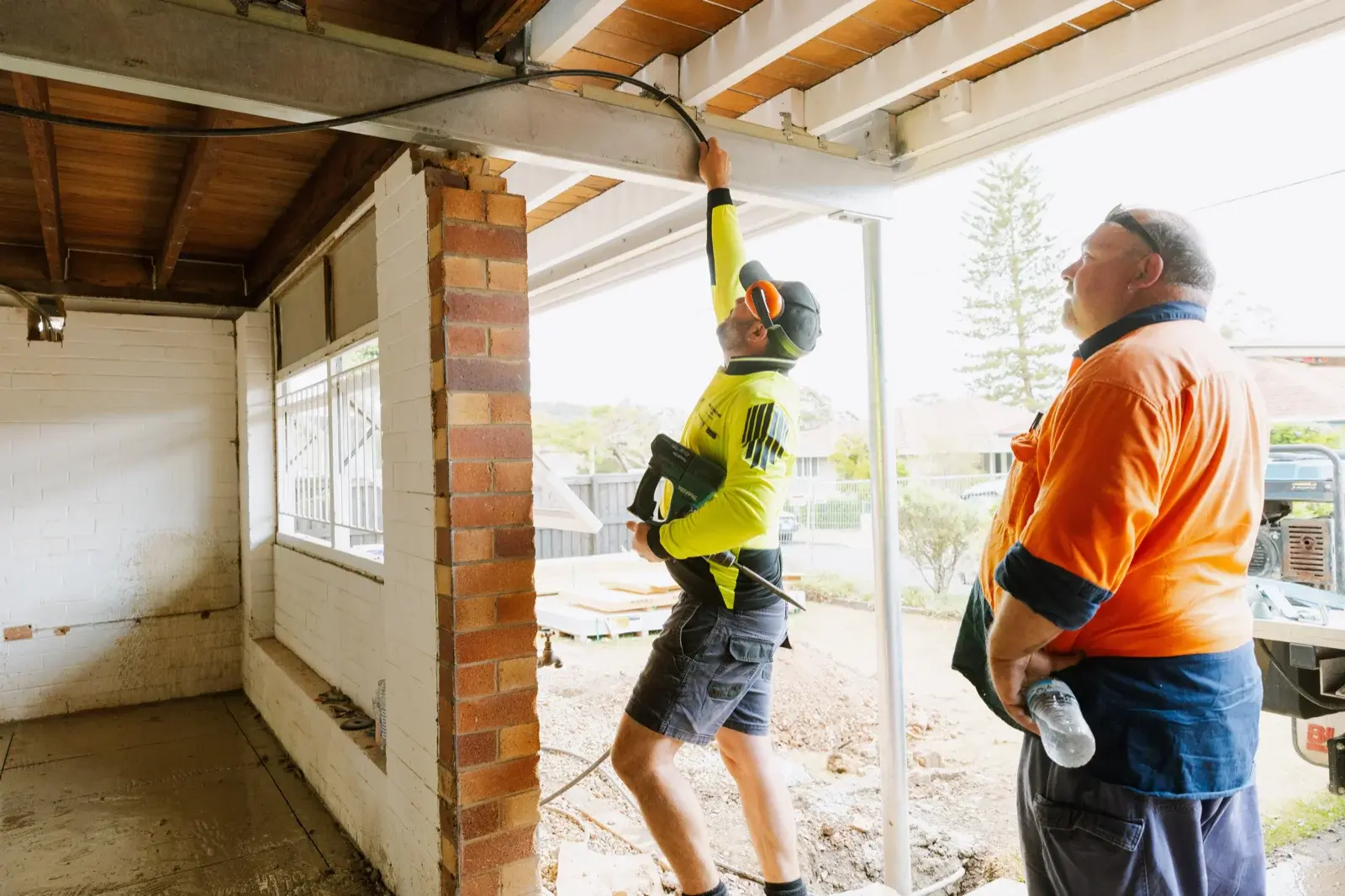 Farr Constructions team installing a structural steel beam during a major home renovation — builder and tradesman coordinating on site in Brisbane