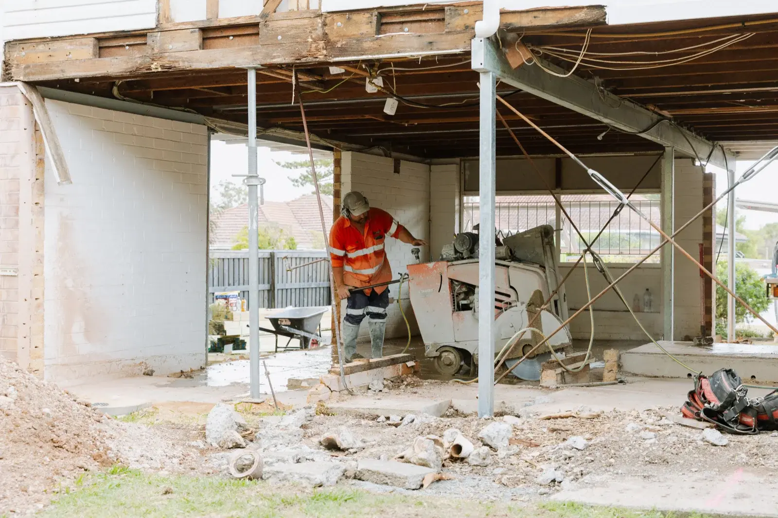 Wide shot of major home renovation demolition in Brisbane — slab removal in progress with heavy machinery on site by Farr Constructions