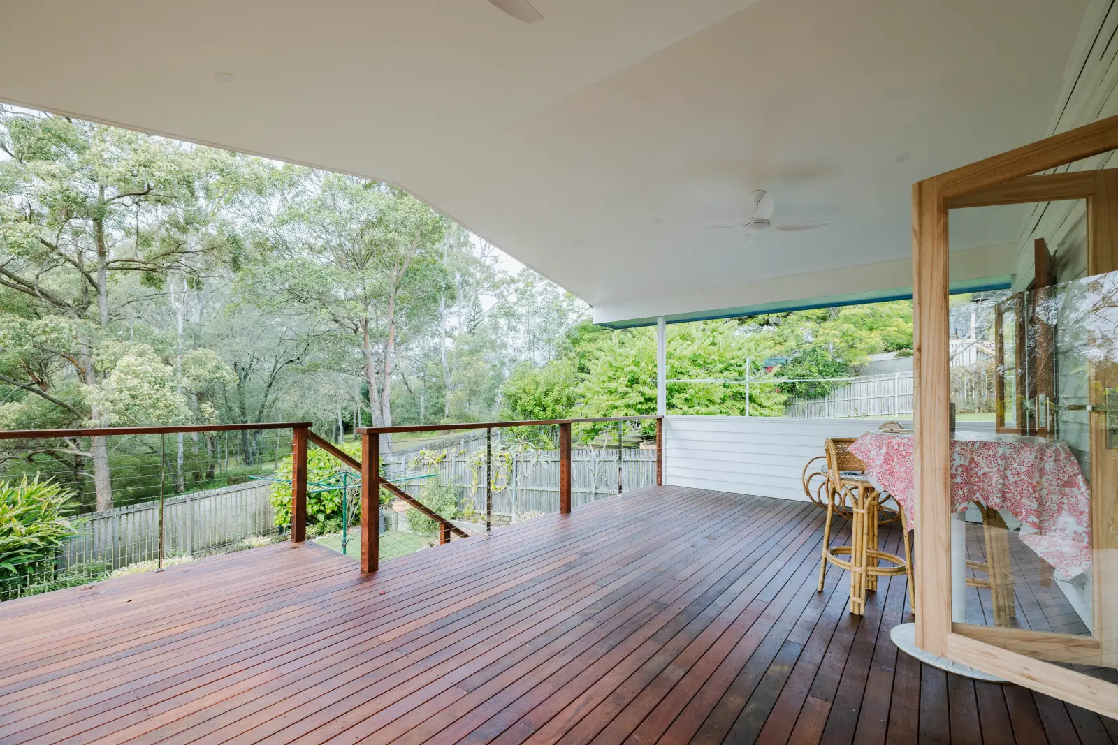 Completed alfresco timber deck with glass railing and leafy outlook by Farr Constructions, Brisbane