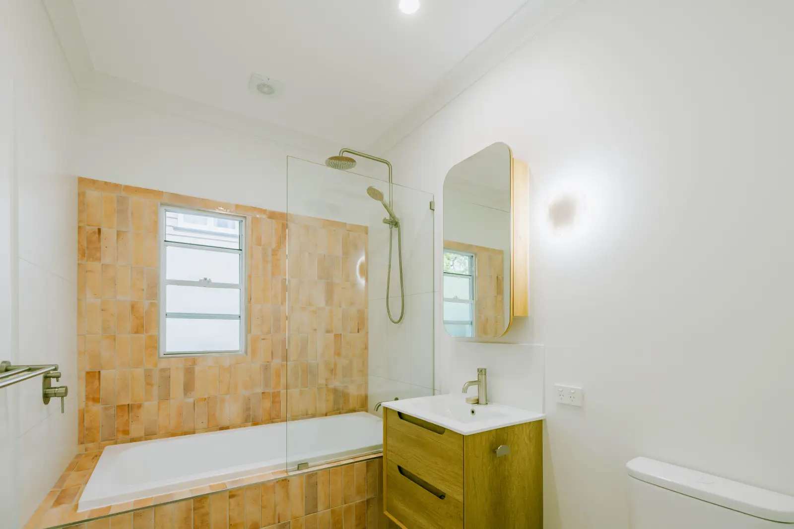 Completed bathroom renovation by Farr Constructions — terracotta tiles, brass shower fittings and custom mirror, Brisbane