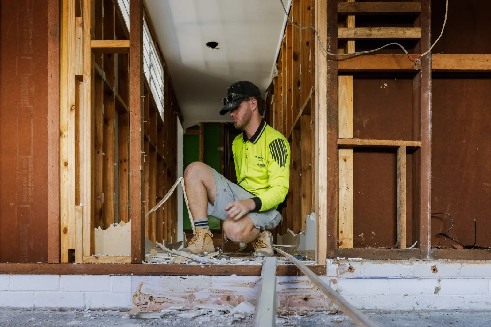 Farr Constructions tradesman assessing lower-level hallway framing during Tarragindi internal renovation, Brisbane