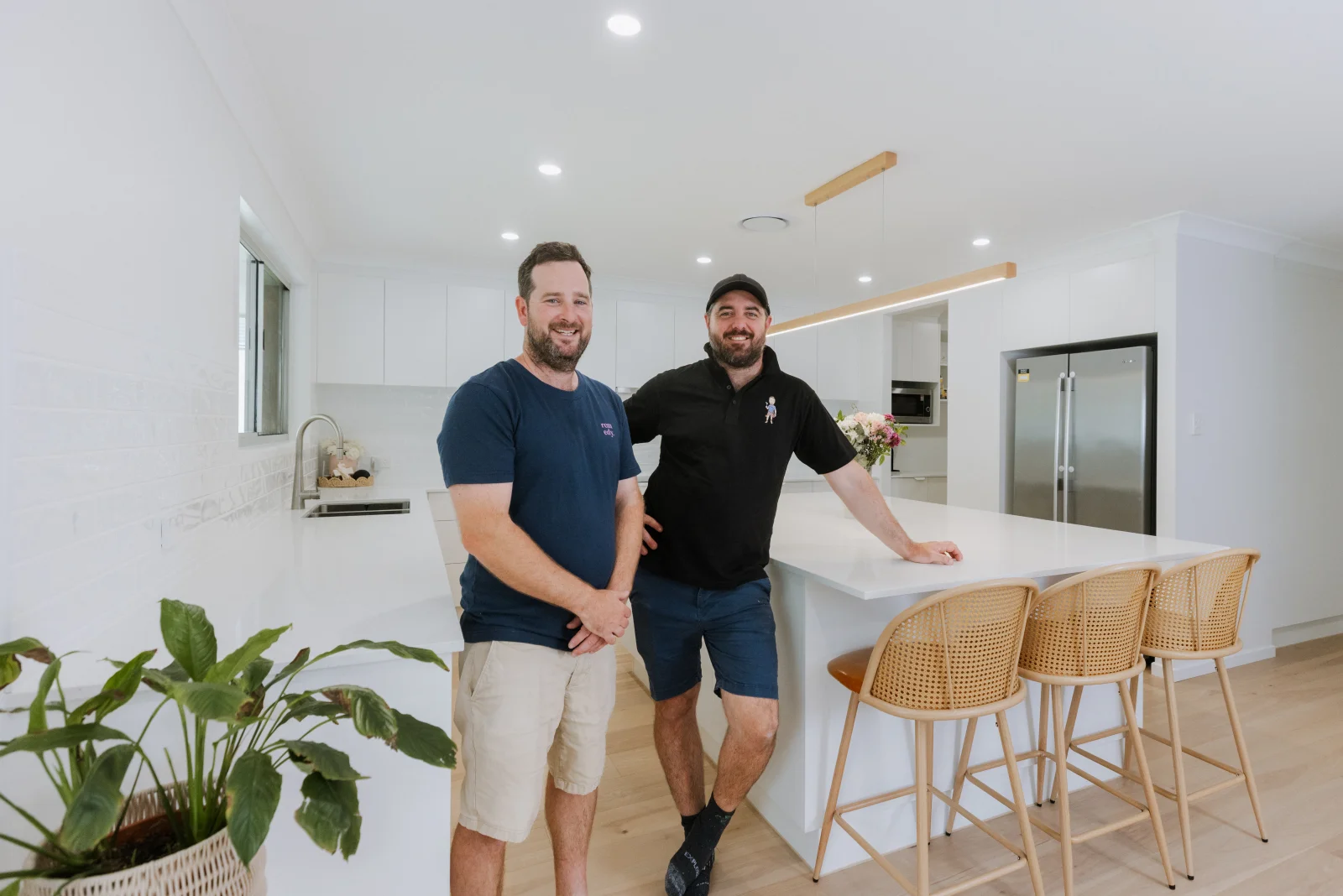 Completed white kitchen renovation Brisbane — Farr Constructions builder with homeowners at island bench