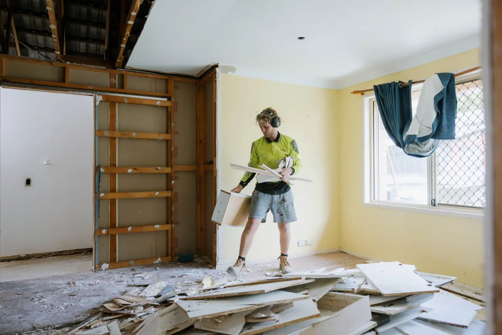 Living room demolition at Taigum home renovation — walls stripped and debris cleared showing full gut scope